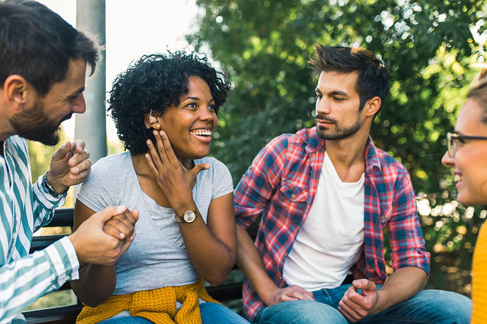 Woman with ear hearing problem having fun with her friends in the park